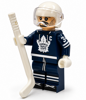 A LEGO minifigure of a Toronto Maple Leafs hockey player holding a white hockey stick, set against a plain white background.